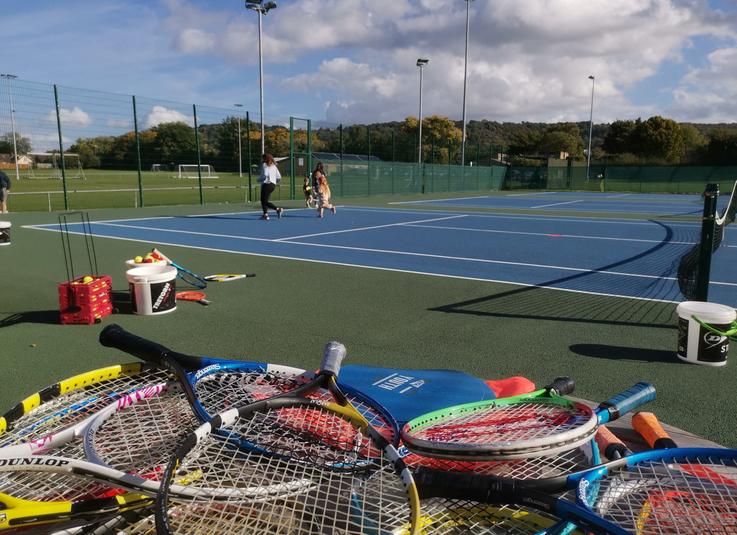 Image of a Tennis court with a pile tennis rackets on the ground.