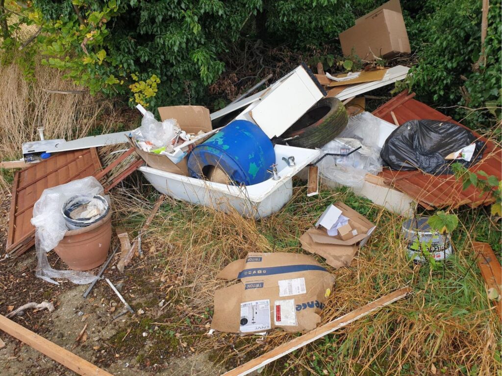 Photograph of rubbish including tyres, a bathtub, and renovation waste