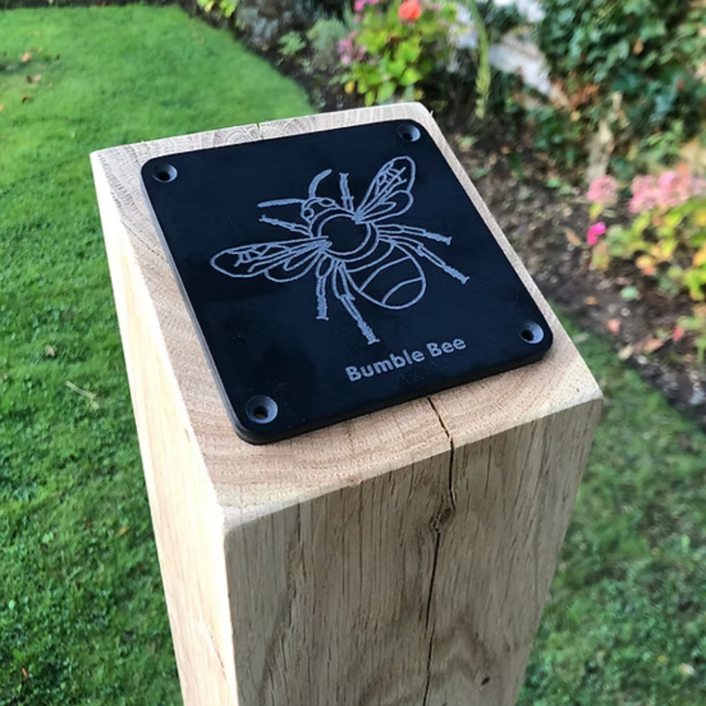 A rubbing plate on a wooden pole with the image of bumble bee