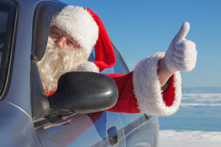 Father Christmas sat in a car with his thumb up out of the window