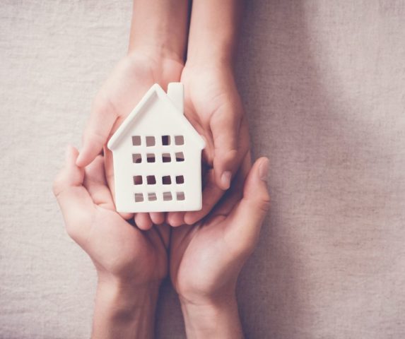 two pairs of hands holding a house