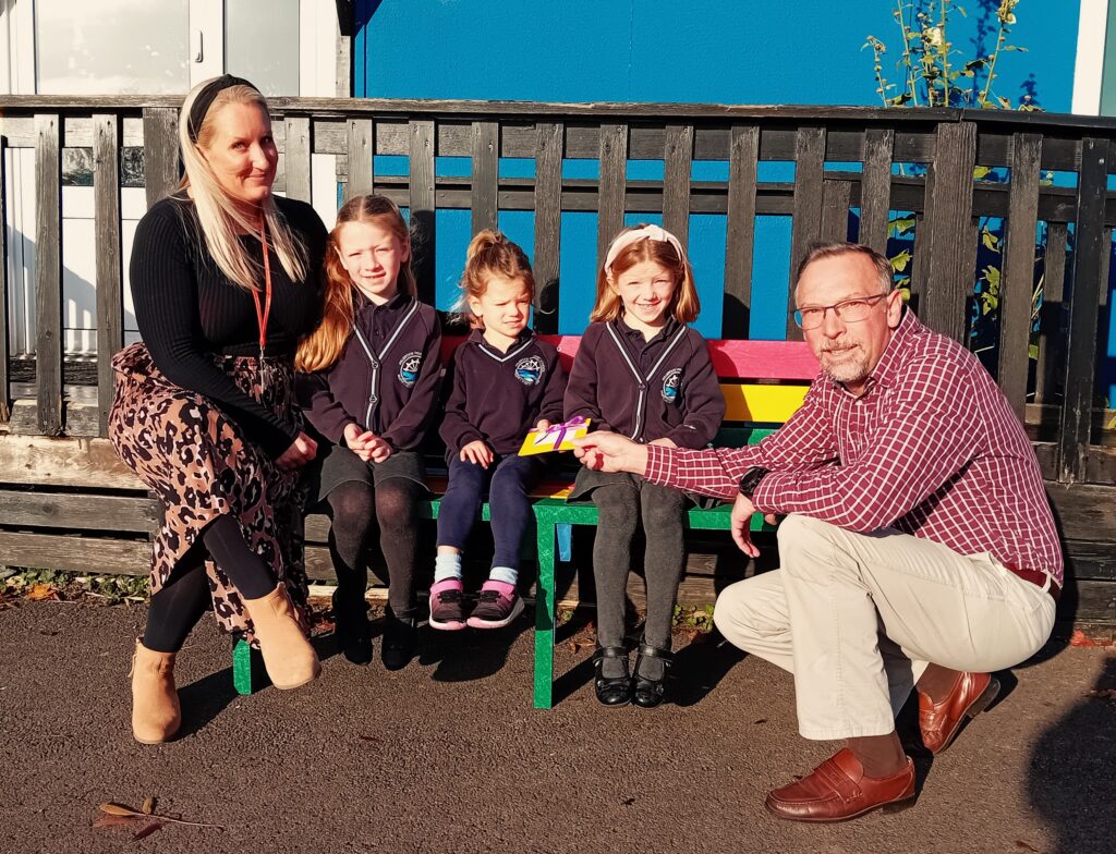 Photo of (l-r) head teacher Mrs Charlton, Georgia, Emilia and Niamh and Cllr Mark Coleman on the colourful new bench